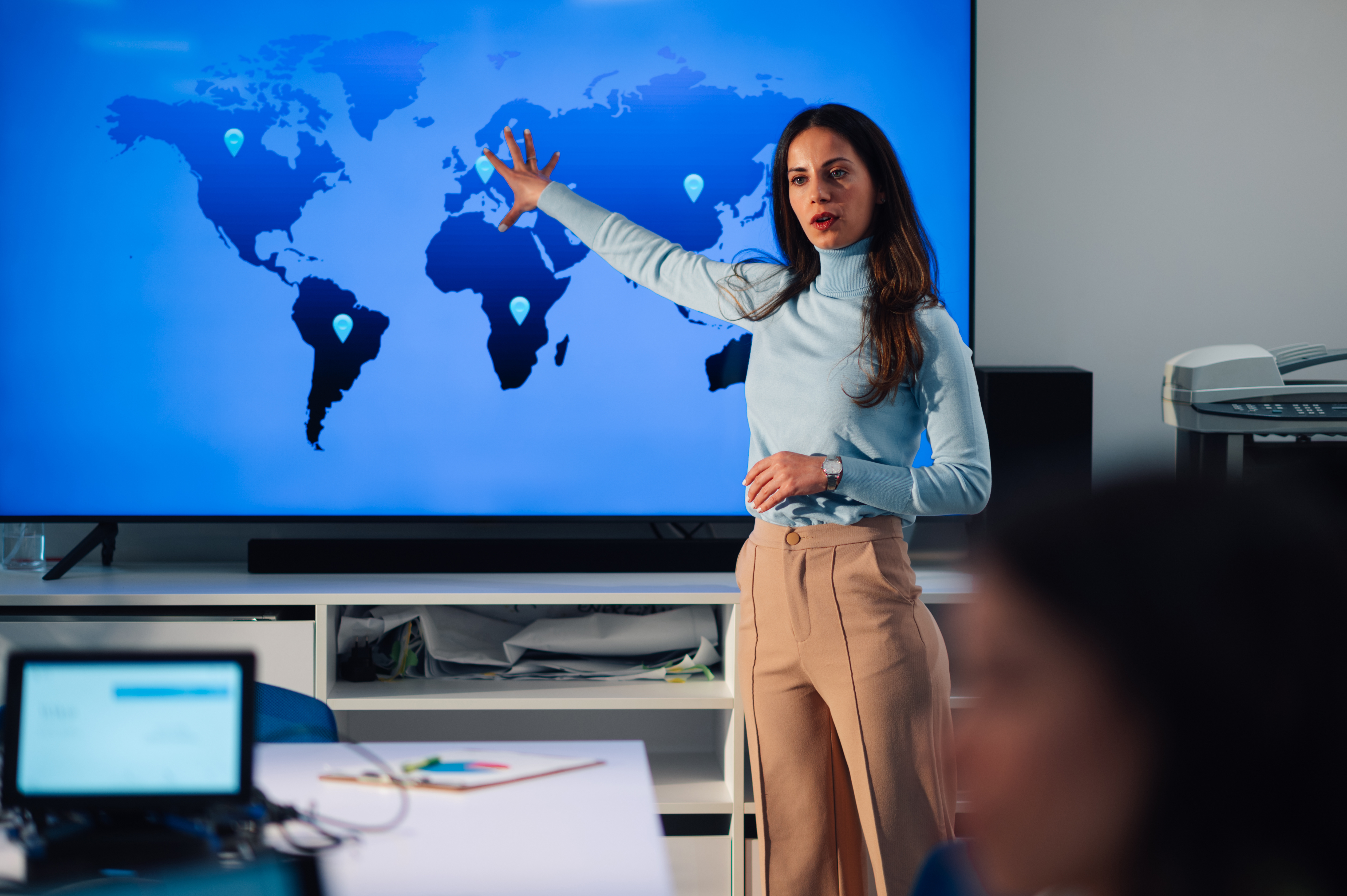 An analyst presents a global map during a business briefing, illustrating AI's worldwide economic impact